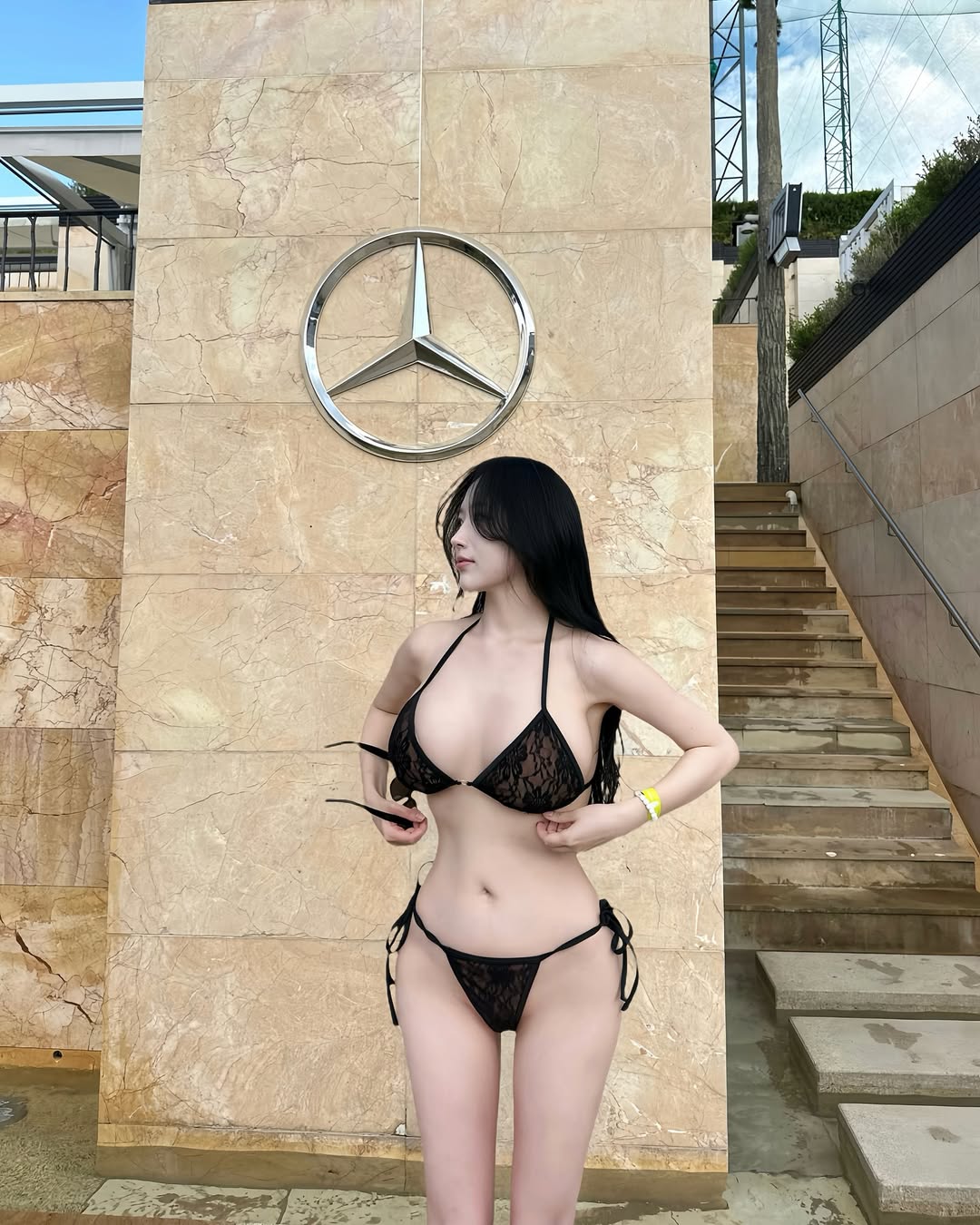 메르세데스 엠블럼이 있는 베이지 스톤 벽 앞에서 블랙 비키니를 입은 김영주 전신 스타일